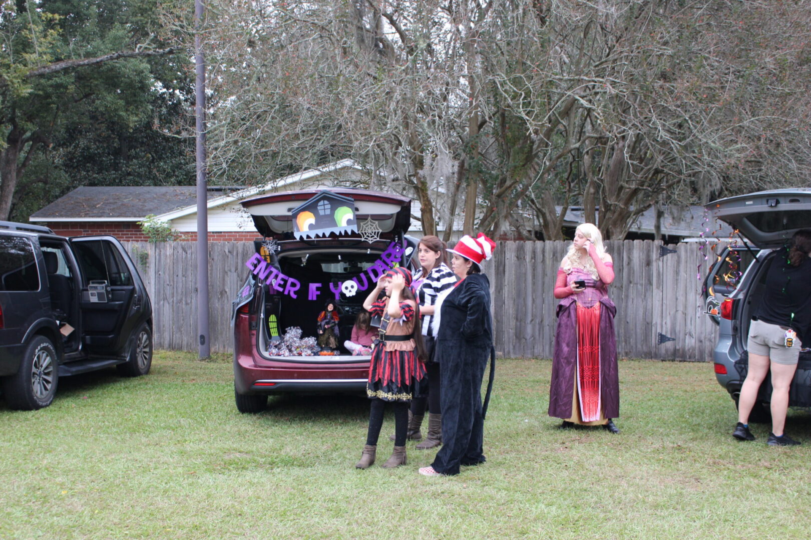 Three people standing in front of a trunk with decorations on it.